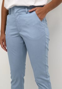 Ljusblå byxor i ett slätt tyg med slim fit, sidfickor och rak frontdesign.