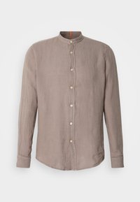 Chemise beige en lin à manches longues avec col mandarin et patte de boutonnage devant sur fond blanc.