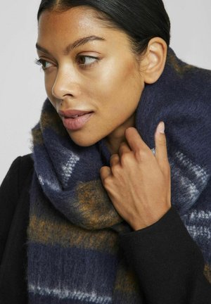 Écharpe rayée bleu marine et or en tissu doux et texturé, drapée autour du cou. Elle présente une surface duveteuse et un motif subtil.