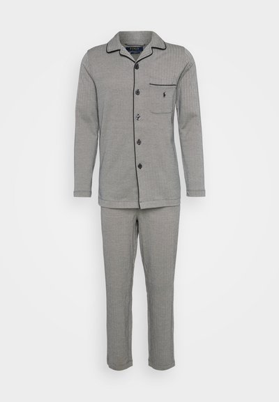 Pilkas pižamos komplektas, kuriame yra marškiniai su mygtukais, kišene ir kontrastinėmis siūlėmis, suderinti su atitinkamomis kelnėmis. Pagaminta iš minkštos, tekstūruotos medžiagos.