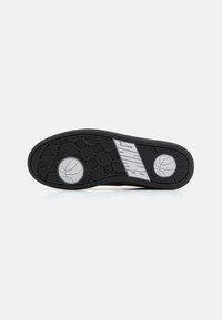 Semelle en caoutchouc noir pour baskets avec un motif texturé, graphique de basketball blanc, et le texte de la marque « EWING » en lettres grises en gras.