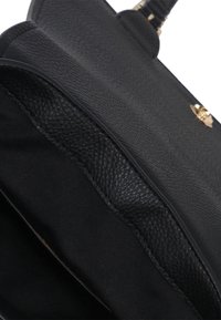 Primo piano di una borsa a tracolla nera in pelle aperta, che mostra il pattina in pelle texture, l'interno in tessuto e i dettagli della chiusura in tonalità dorata.