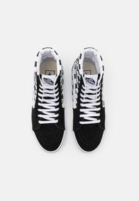 Para czarno-białych sneakersów Vans typu high-top z wzorem w szachownicę po bokach i białymi sznurówkami, widziana z góry na białym tle.