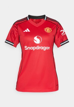 Camisa de futebol vermelha com decote em V, detalhes em preto nas mangas e um logótipo no peito. O tecido tem uma textura suave e um design respirável.