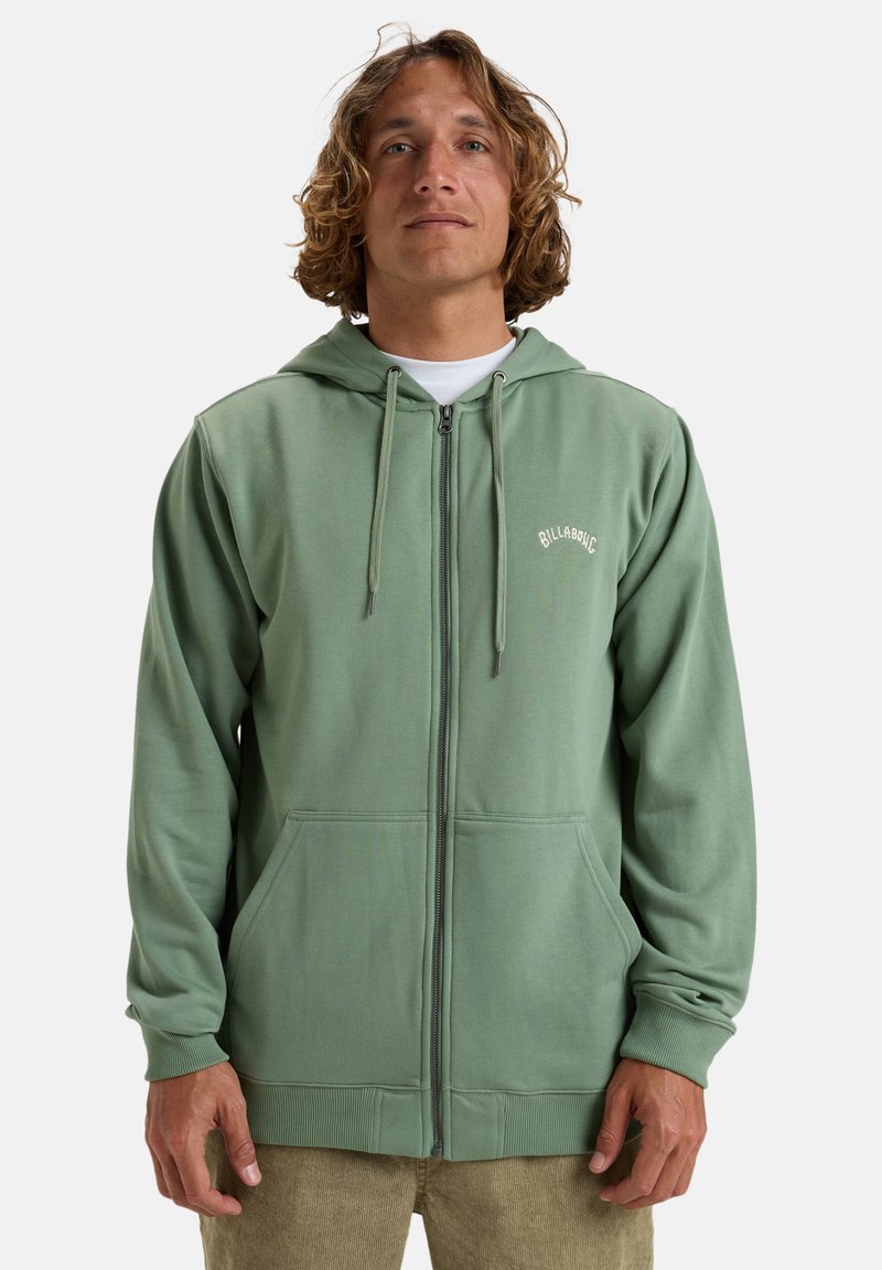 Grüne Zip-Hoodie aus weichem Stoff, mit einer Fronttasche, Kordelzugkapuze und dezentem Logo-Stick auf der Brust.
