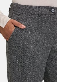 Graue Tweed-Hosen mit einem subtilen Fischgrätenmuster, ausgestattet mit einem Knopfverschluss und seitlichen Taschen; glattes, strukturiertes Material.