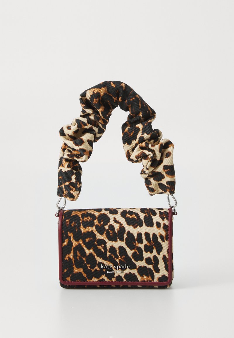 Sac à main en imprimé léopard avec une poignée style chouchou. Fabriqué en tissu texturé avec une bordure bordeaux. Présente un logo en blanc sur le devant.