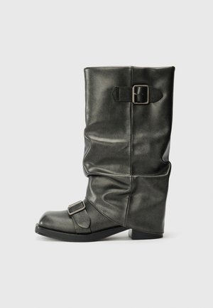 Must have nahketaoline musta värvi ankle boot, millel on lahtine vars, paks konts ja kaks metallist pandlat külgedel detailideks.