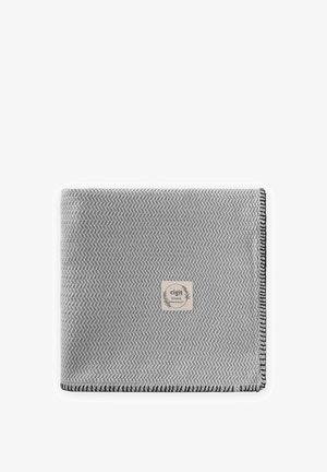 Couverture grise pliée avec un motif chevron subtil, bords cousus noirs, et une étiquette beige au centre portant l'inscription « cigit BOHEME qualité premium ».