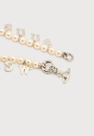 Βραχιόλι με πέρλες σε λευκό φόντο, με ασημένιο στρογγυλό κούμπωμα και μοτίφ με γράμματα, μεταξύ των οποίων ένα μοτίφ σε σχήμα πλανήτη.
