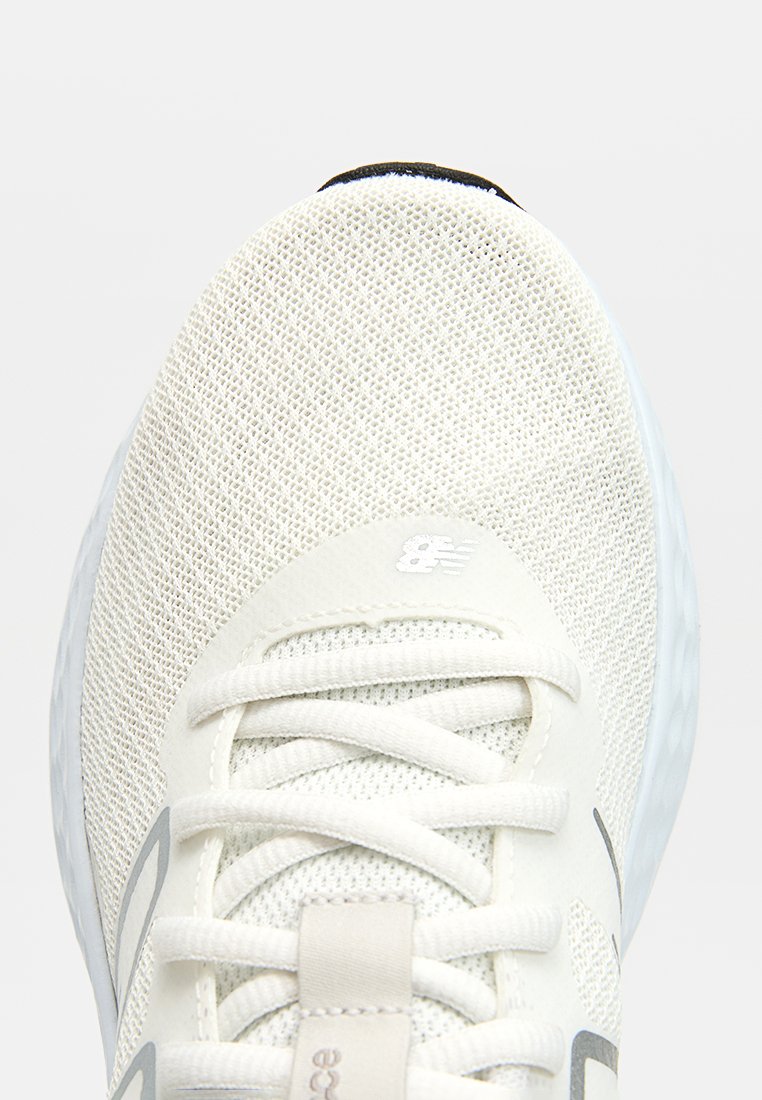 Chaussure de course en maille légère de couleur blanc cassé ; dispose de lacets plats, d'une languette rembourrée et d'une semelle intermédiaire texturée avec de subtils accents gris et un logo.