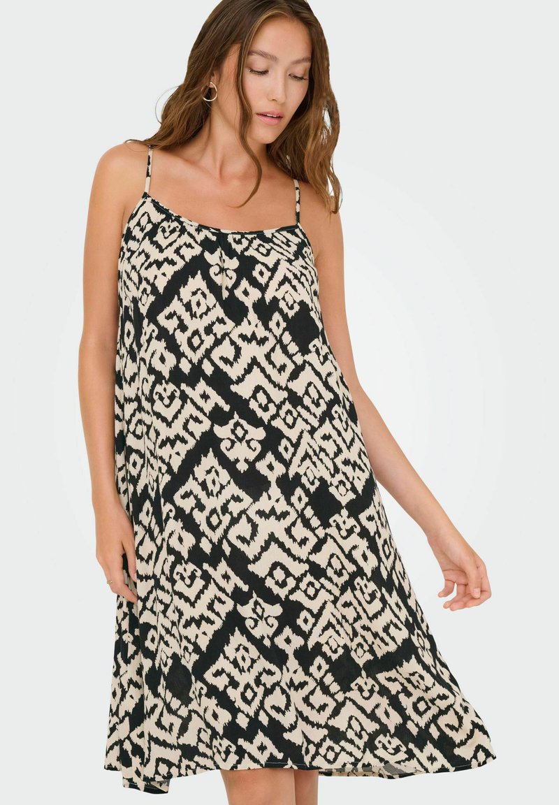 Zwart en beige patroon jurk met een losse pasvorm, spaghettibandjes en een vloeiende silhouet, met een geometrisch ontwerp overal.