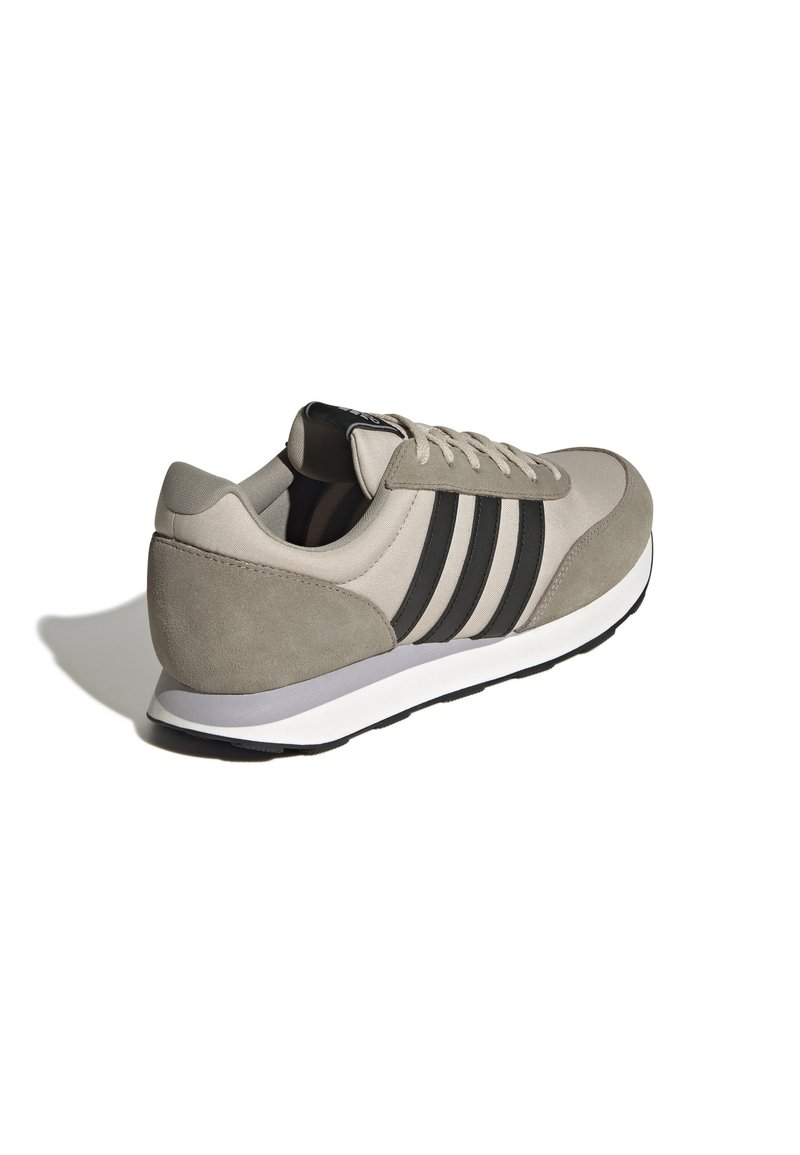Beige en grijze sportschoen van suede en mesh materialen, met drie zwarte strepen, een ronde neus, vetersysteem en een witte tussenzool.