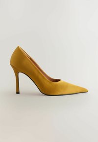 Keltainen satiininen korkokenkä, jossa on kapeneva kärki, kaareva siluetti ja musta pohja, esittelee sileän tekstuurin ja elegantin muotoilun.
