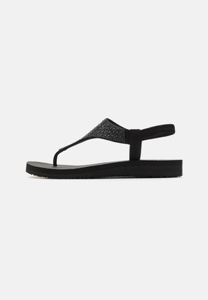 Črne sandale na flip-flop z teksturirano naramnico in oblazinjenim podplatom, zasnovane v slogu T-bar z teksturiranimi detajli.