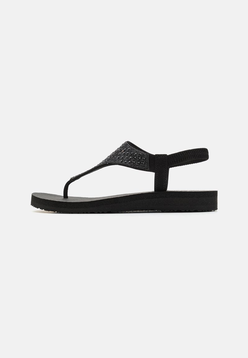 Mustat flip-flop-sandaalit, joissa on teksturoitu hihna ja pehmeä pohja. Suunniteltu T-bar-tyyliin ja teksturoiduin yksityiskohdin.