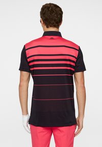 Koszulka polo z krótkim rękawem w kolorze czarnym i intensywnym różowym, z poziomymi paskami i kołnierzykiem. Materiał jest gładki, o sportowym kroju.