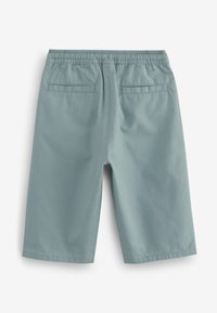 Ljus teal kortbyxor tillverkade av slät tyg, med resårmidja och två bakfickor med en ren, minimalistisk design.