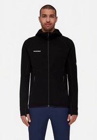 Zwarte fleecejack met capuchon en volledige ritssluiting, voorzien van zijzakken, een getailleerd ontwerp en een logo op de borst en mouw.