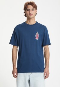 Mørkeblå kortærmet t-shirt i en bomuldsblanding med et grafisk design, der viser en pink figur og teksten "STONE" i en diamantform på brystet.