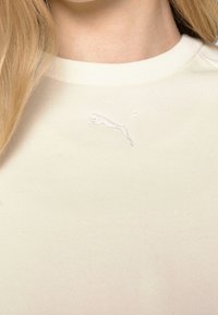 Krämfärgad bomullströja med en subtil brodyr av Puma-logotypen på bröstet, klassisk rund hals och textil med struktur.