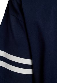 Temno modra bombažna majica s tremi vodoravnimi belimi črtami na rokavih. Tkanina ima gladko teksturo in klasičen kroj.