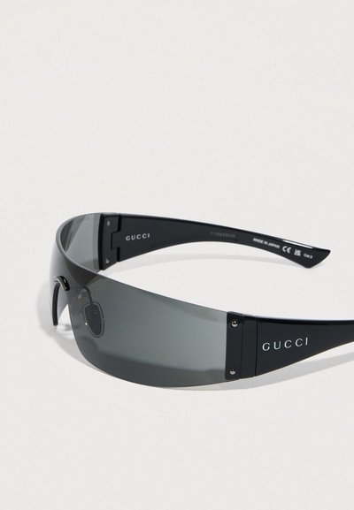 Guccin aurinkolasit tummanharmailla linsseillä, tyylikäs musta kehys ja metallikoristeet. Suunnittelussa on minimalistinen, aerodynaaminen muoto.