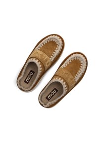 Des chaussures slip-on en suède beige avec un accent tissé beige autour de l'ouverture, dotées d'une doublure intérieure douce et d'une semelle moulée.