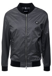 Svart bomberjacka med ett texturerat mönster, med dragkedja fram, ribbade ärmslut och två sidofickor. Tillverkad av ett mjukt, lätt material.