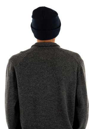 Gorro de canalé azul marino con puño doblado, que se lleva sobre un suéter de punto gris con cuello redondo y mangas raglán.