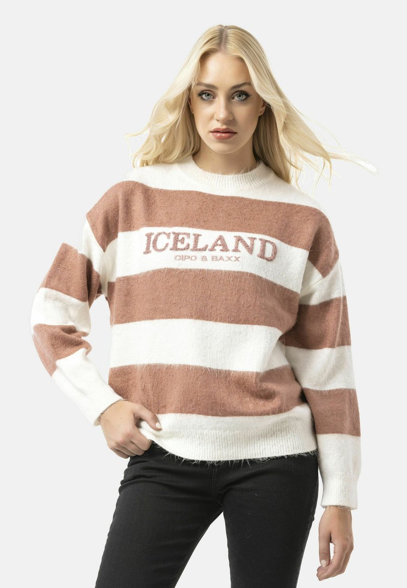 Gestreepte trui in wit en zacht bruin, gemaakt van gestructureerd materiaal, met een ronde hals en het woord "ICELAND" in geborduurde letters.