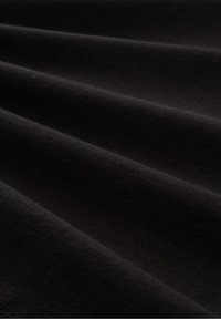 Gros plan d’un tissu noir lisse avec des plis subtils et une texture douce.