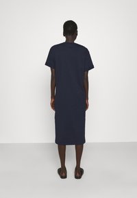 Granatowa sukienka z bawełny T-shirt z krótkimi rękawami, długości do kolan, prosty krój, miękka tekstura i minimalne detale.
