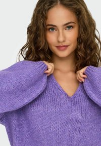 Maglione lavorato a maglia viola con scollo a V, maniche oversize e una finitura testurizzata. Tessuto morbido con sottili accenti di lucentezza.