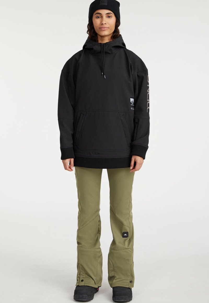 Schwarzer Kapuzenpullover mit großer Fronttasche und Kordelzugkapuze, kombiniert mit olivgrünen Schneehosen, die ein seitliches Logo-Patch haben.