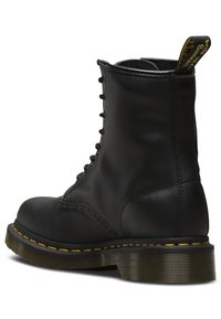 Stivaletto in pelle nera con design lacciato, cuciture gialle e suola spessa e testurizzata. Presenta un'etichetta del brand sul retro.