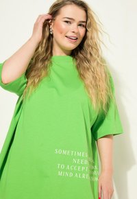Camiseta de algodón verde de gran tamaño con mangas cortas y texto blanco que dice "A VECES NECESITAS ACEPTAR LO QUE TU MENTE YA CONOCE."