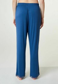 Blauwe, lichte, elastische broek met een relaxte pasvorm, voorzien van kantafwerking aan de zoom voor extra detail.