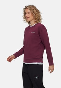 Sweatshirt bordeaux con colletto a girocollo e maniche lunghe, con un logo bianco sul petto. Materiale morbido, vestibilità casual e polsini a coste.