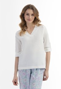 Hvid linned-top med v-hals og opsmøgede ærmer, parret med lyseblå blomstrede pyjamasbukser med lilla og hvide blomster.