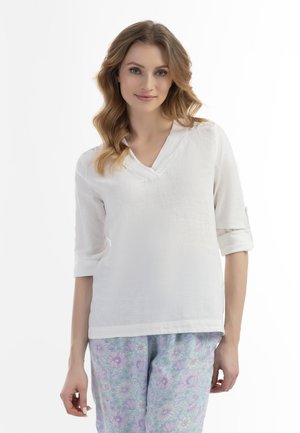 Hvid linned-top med v-hals og opsmøgede ærmer, parret med lyseblå blomstrede pyjamasbukser med lilla og hvide blomster.