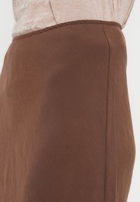 Jupe marron en tissu doux et texturé, présentant un design simple et droit avec des bords cousus.