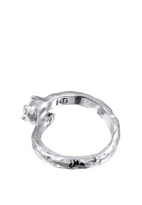 Srebrn prstan z teksturirano band in izstopajočo nastavitvijo dragulja na eni strani. Ima edinstveno, nepravilno obliko.