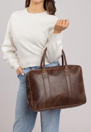 Brązowa skórzana torba tote z podwójnymi uchwytami, zamkiem błyskawicznym i akcentami w kształcie diamentów. Gładka tekstura z eleganckim wzornictwem.