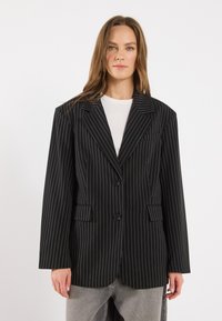 Black striped blazer with a tailored fit, wide lapels, two buttons, and front pockets. The fabric has a smooth texture with vertical pinstripes.