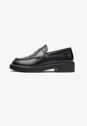 Black leather loafers featuring brogue detailing, a slightly rounded toe, raised stitching, and a low, textured rubber heel.