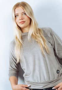 Grijs, shirt met lange mouwen van een zachte, gestructureerde stof. Heeft een ronde halslijn en een klein logo aan de onderzijde. Casual pasvorm.