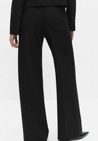 Czarne spodnie z szerokimi nogawkami o gładkiej fakturze i dopasowanym kroju, z wysokim stanem i subtelnymi detalami w postaci przeszyć.
