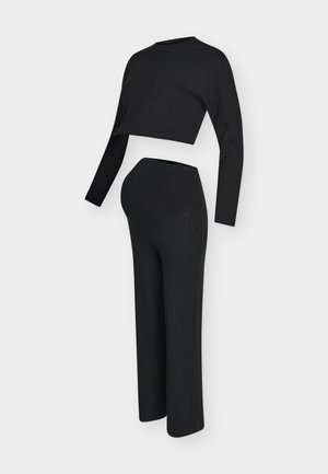 Set da casa nero a coste con top a maniche lunghe corto e pantaloni a vita alta. Materiale morbido, sagoma aderente e design minimalista.