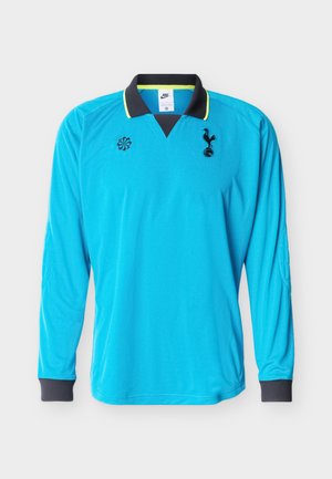 Φωτεινή μπλε ποδοσφαιρική φανέλα με μακριά μανίκια, μαύρο γιακά, μαύρα μανσέτα και κεντημένο λογότυπο ομάδας και σήμα χορηγού στο στήθος.